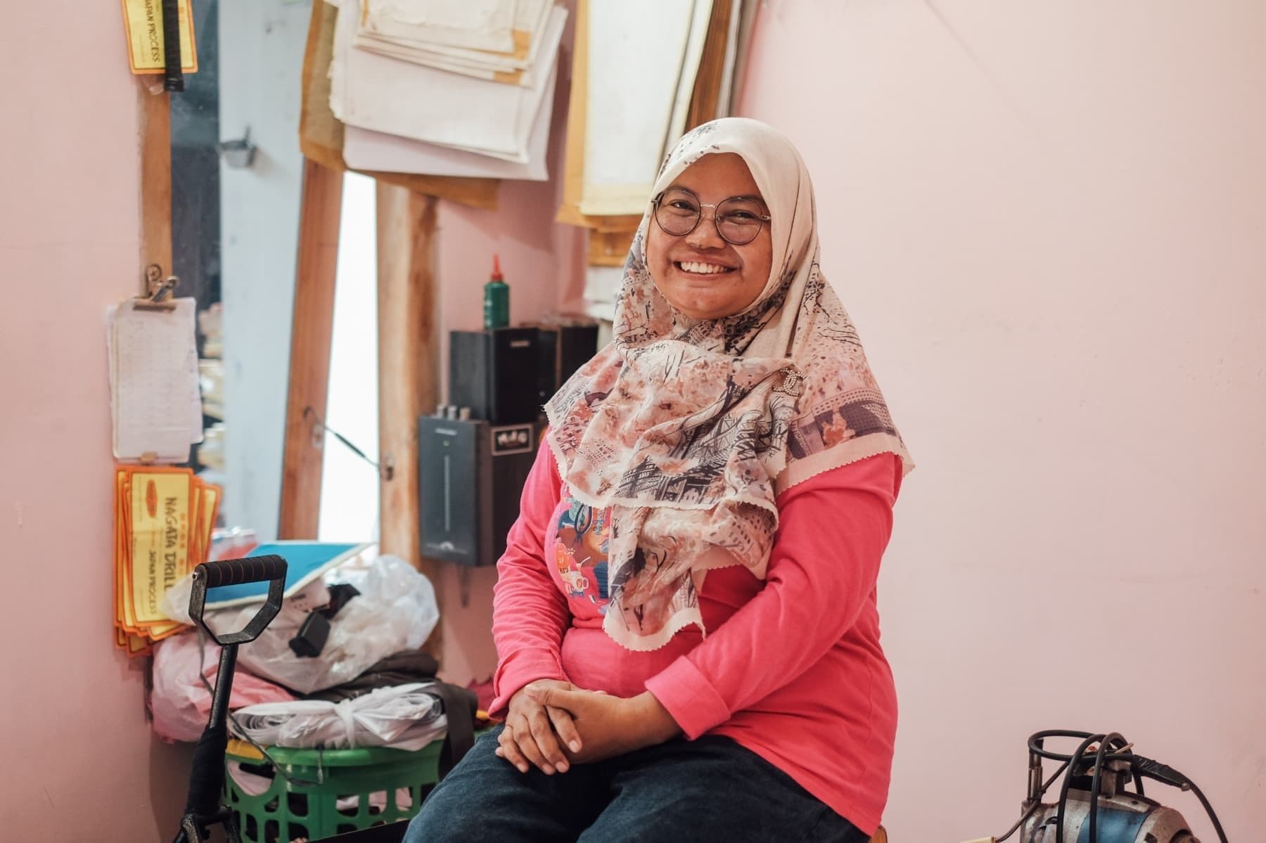 Foto Ibu Rani sedang terduduk sembari tersenyum menghadap ke kamera.