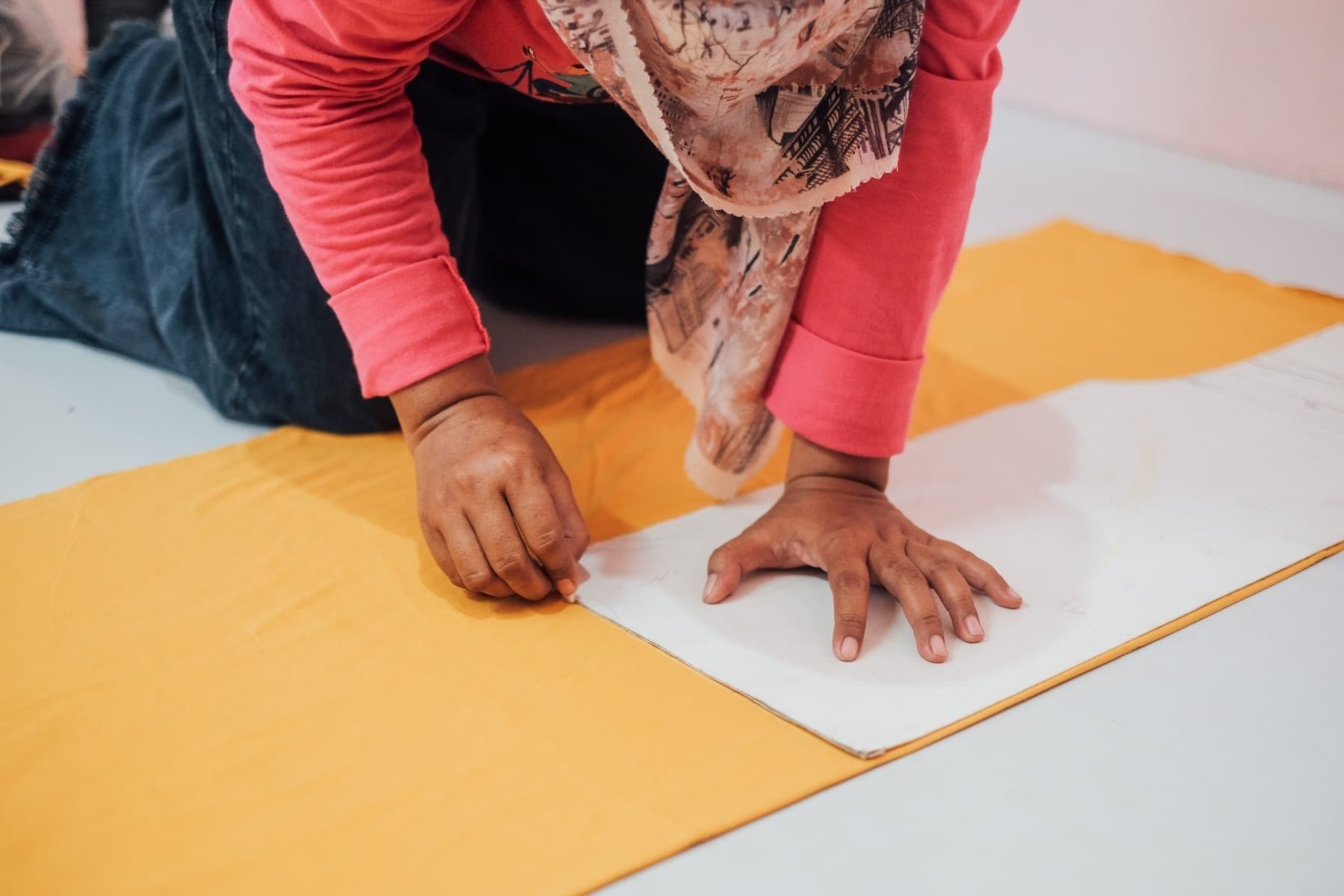Foto Ibu Rani sedang menggambar pola kaos di atas material kain.