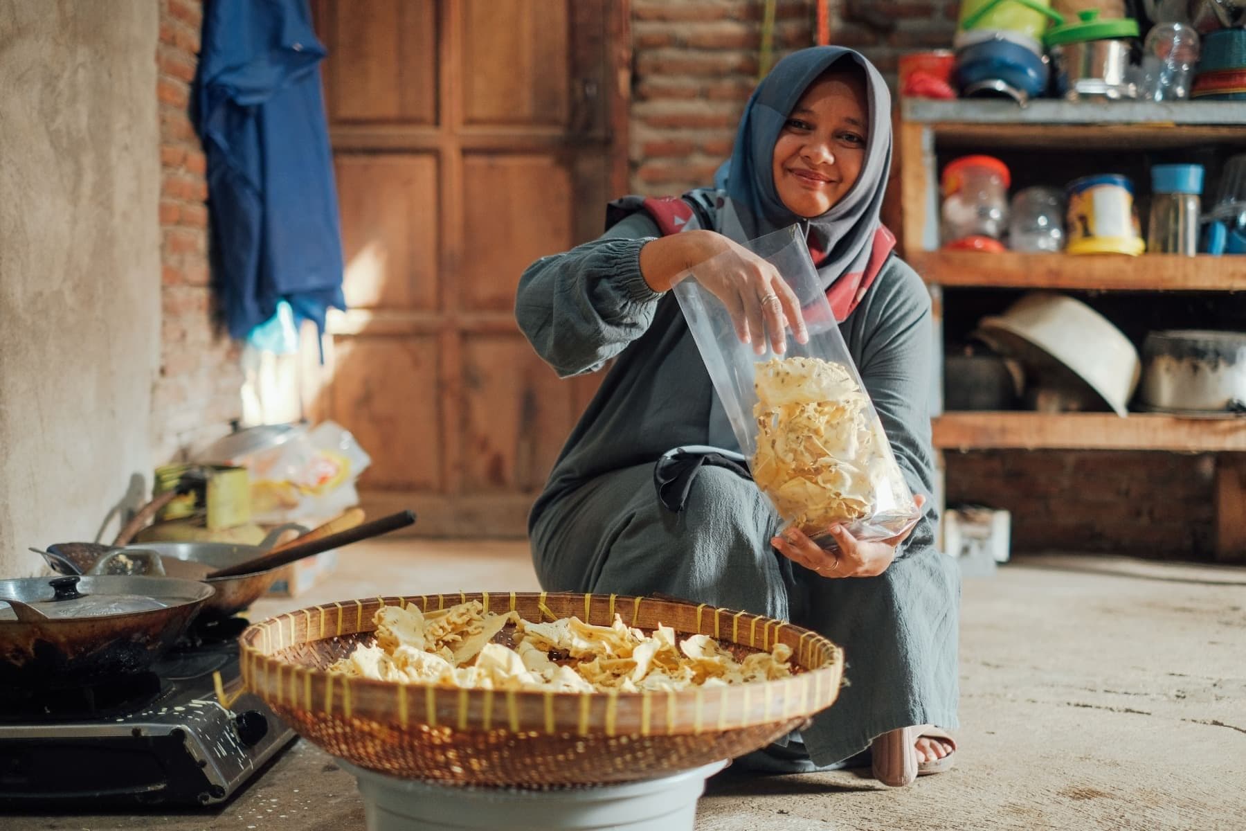 Foto Ibu Ayu sedang memasukkan rempeyek ke dalam plastik
