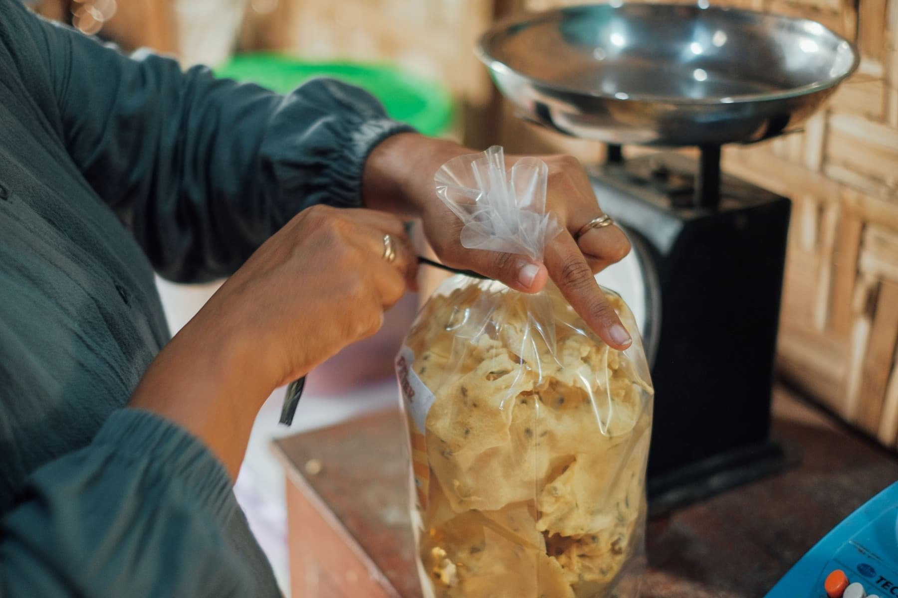 Foto Ibu Ayu mengikat plastik yang berisi rempeyek di atas meja.