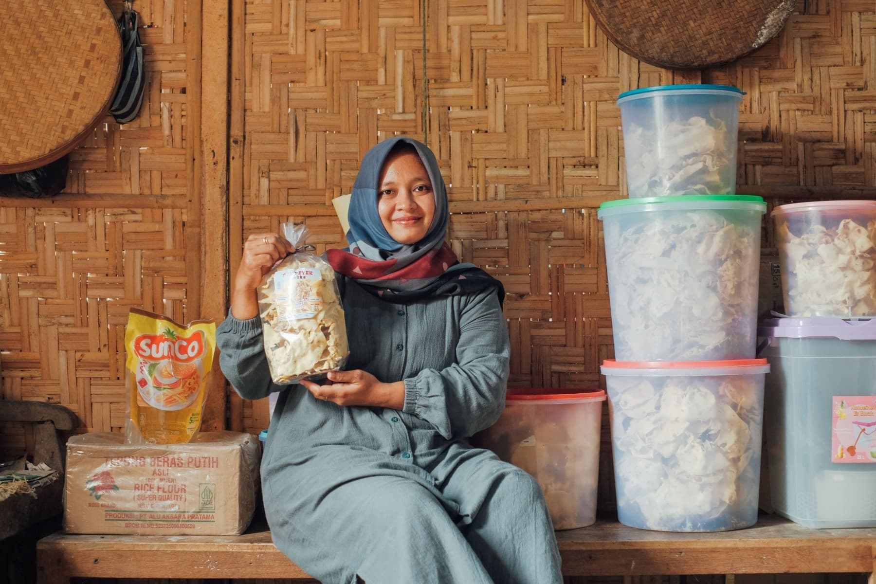 Foto Ibu Ayu mengangkat plastik yang berisi rempeyek sembari tersenyum