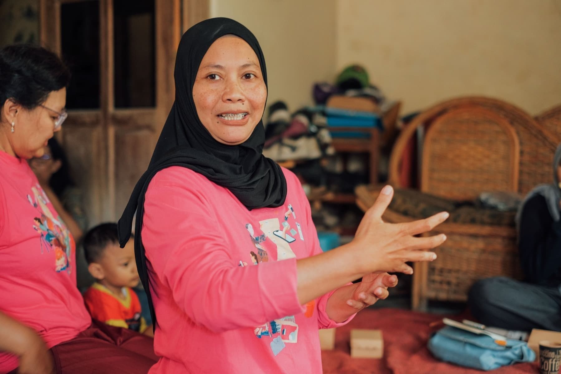 Foto Ibu Ida sedang berbicara kepada audiens menggunakan gesture tangan.